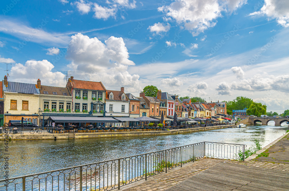 Fototapeta premium Amiens old town Saint-Leu quarter, embankment promenade of Somme river with street restaurants, traditional houses and Pont du Cange stone bridge in historical centre, Hauts-de-France Region, France