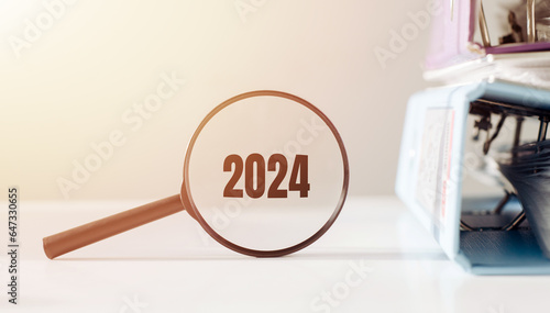 Magnifier with word numbers 2024 on iffice desk background. Focused on business concept. Search new idea