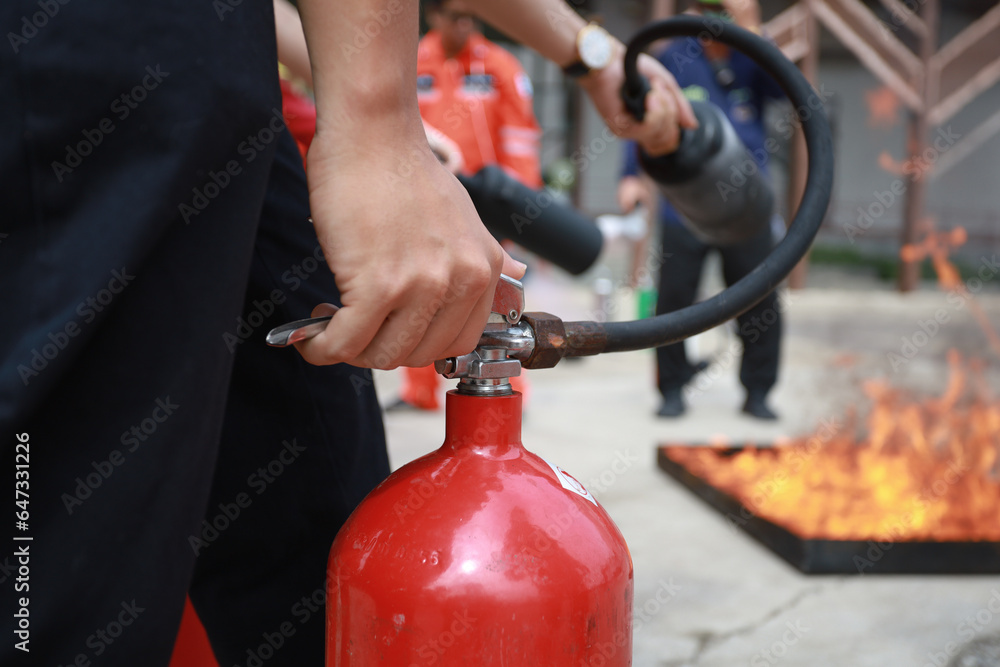 Fototapeta premium Employees firefighting training, Concept Employees hand using fire extinguisher fighting fire closeup