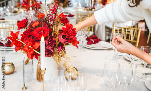 Red gold color flower decor for Chinese New Year celebration. Girl woman florist, decorator, organizer of events, parties, wedding planner making floral arrangement, festive bouquet, table decoration