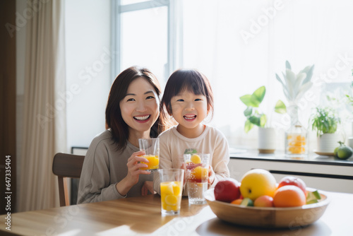 Happy Asian family Mother and Little girl are eating breakfast, drinking milk and drinking orange juice in the kitchen at home.