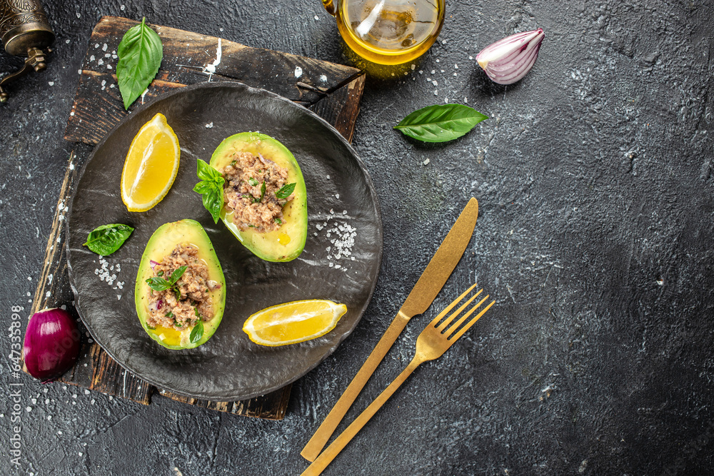 Avocado boats stuffed with tuna on a dark background. banner, menu, recipe place for text, top view