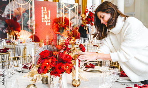 Red gold color flower decor for Chinese New Year celebration. Girl woman florist, decorator, organizer of events, parties, wedding planner making floral arrangement, festive bouquet, table decoration