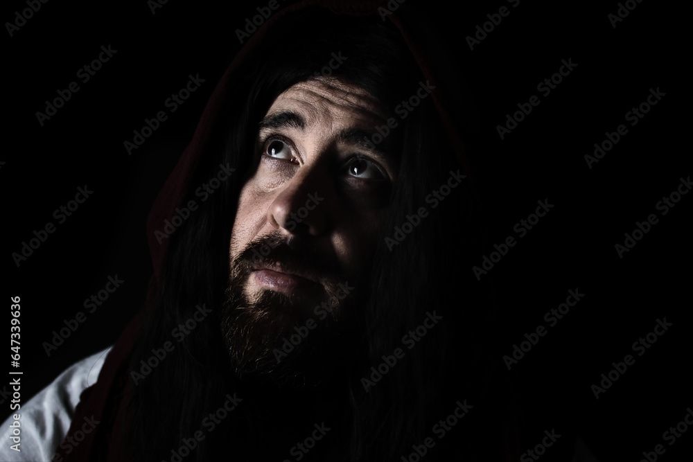 portrait of model dressed as Jesus Christ or biblical character with shawl over head and beard looking up to sky or God prayer portrait of model dressed as Jesus Christ or biblical character with shawl over head and beard looking up to sky or God prayer