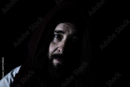 portrait of model dressed as Jesus Christ or biblical character with shawl over head and beard looking directly at camera with emotion and love