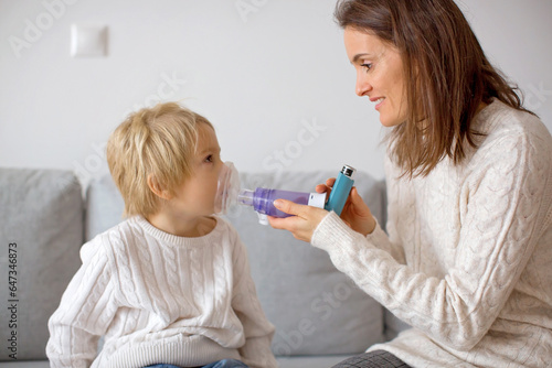 Mother, helping little toddler child with inhaler with spacer