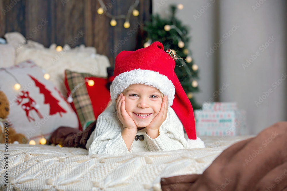 Cute toddler child, boy in a christmas outfut, playing in a wooden cabin on Christmas, derocation around him Cute toddler child, boy in a christmas outfut, playing in a wooden cabin on Christmas, derocation around him