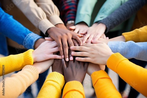 Diverse teenagers unite by placing their hands together in a gesture of solidarity.