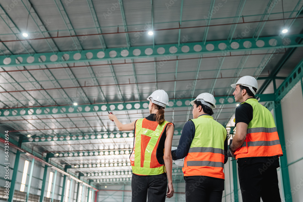 Team engineers workers planning and talking in empty warehouse to design the arrangement of product shelves and organize strategy about new manufacturing. Team engineers workers planning and talking in empty warehouse to design the arrangement of product shelves and organize strategy about new manufacturing.