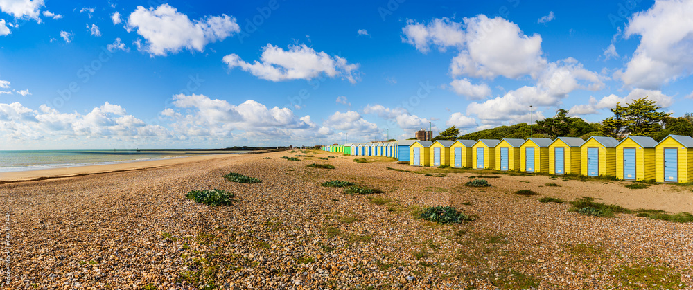 Colorfool beach huts on the shores of Littlehampton Long Beach in Sussex, England, UK; wooden yellow huts on pebbles beach