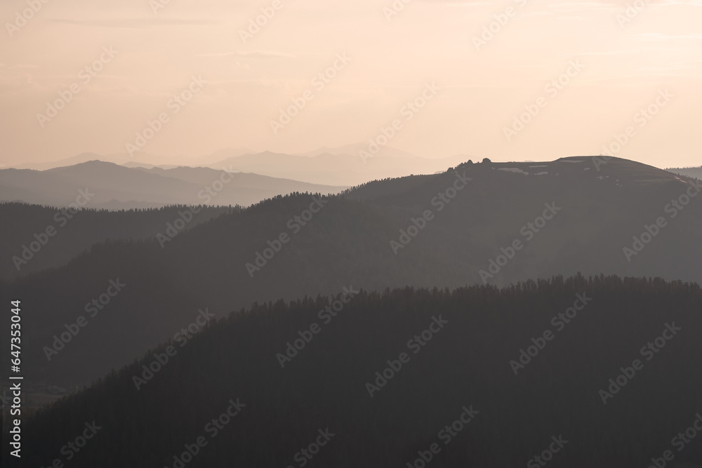 Golden sunset in mountain landscape. Layers of mountains background. Silhouette of the evening mountains at sunset.