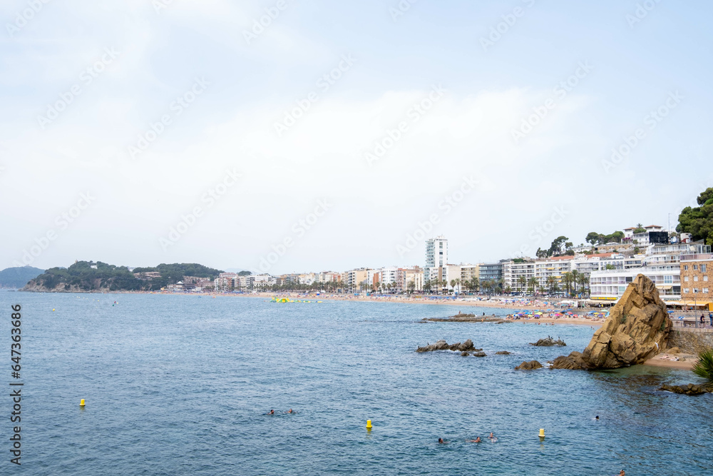Panoramic view of the Costa Brava village of Lloret de Mar, showcasing its expansive beach and buildings in the background.