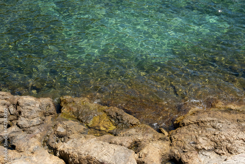 Image of the crystal-clear waters of the Mediterranean Sea in the Costa Brava  with the reflection of the sun on its waves breaking against the rocks.