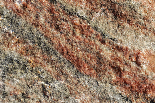 Fotografie Granite stone surface with roughness and unevenness with red and gray veining for use as an abstract background and texture