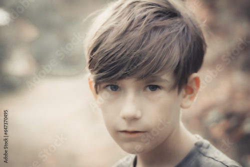 Boy is looking at the photo camera. A child enjoys nature in the forest. Soft selective focus