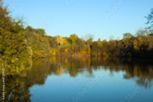 Blurred view of beautiful lake and yellow trees on autumn day