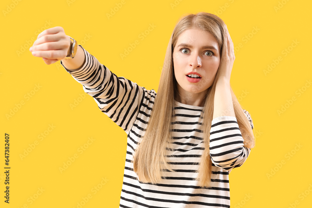 Stressed young woman looking at wristwatch on yellow background. Deadline concept Stressed young woman looking at wristwatch on yellow background. Deadline concept