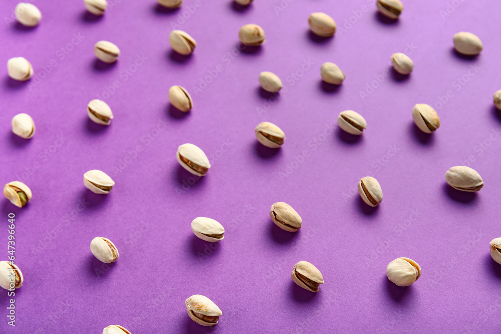 Tasty pistachio nuts on purple background Tasty pistachio nuts on purple background
