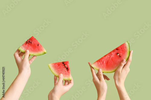 Female hands with slices of fresh watermelon on green background