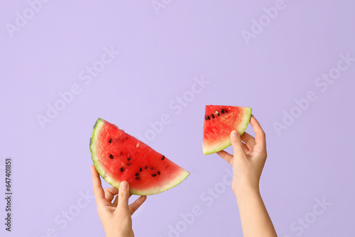 Female hands with slices of fresh watermelon on lilac background