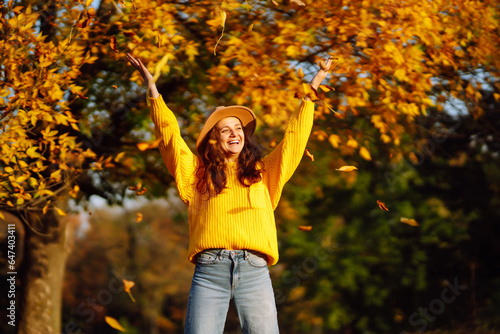Autumn mood. Happy woman in a bright sweater and hat having fun, walking, having a picnic in an autumn park at sunset. The concept of relaxation, walking.