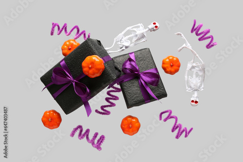 Flying gift boxes, pumpkins, skeletons and Halloween decoration on grey background