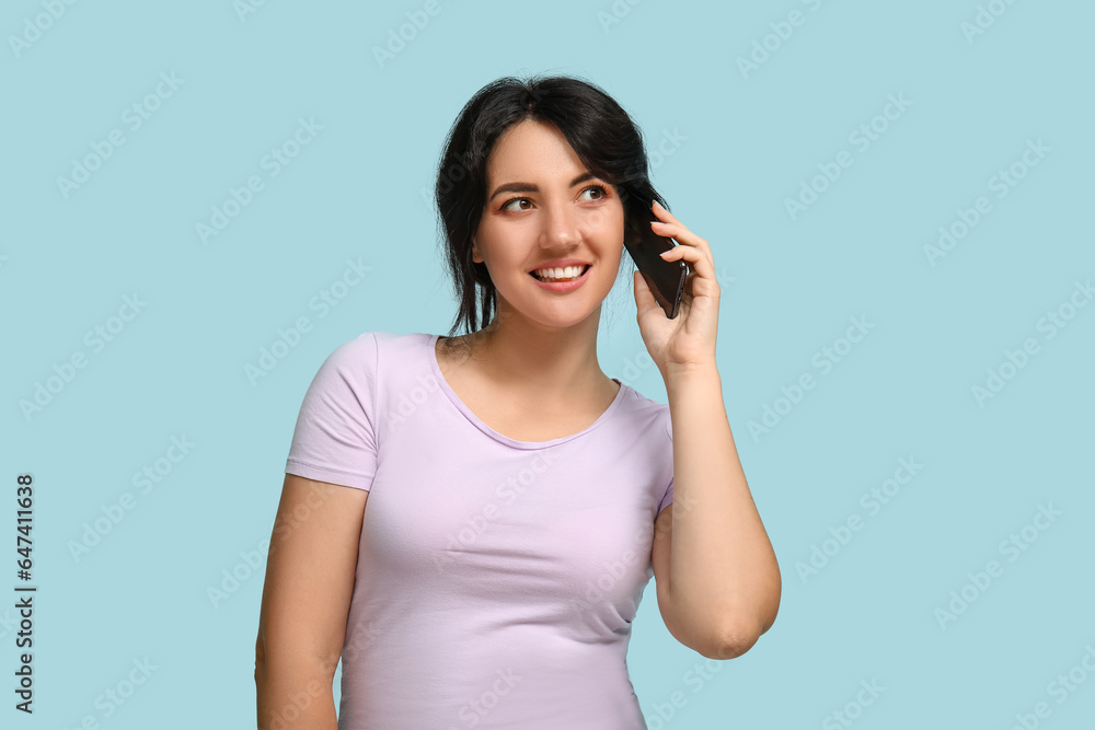 Portrait of happy young brunette talking by phone on blue background Portrait of happy young brunette talking by phone on blue background