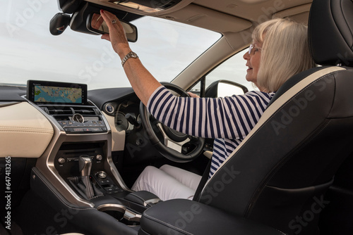 Southsea, Portsmouth, England, UK. 29 August 2023. Lady driver adjusts the rear view mirror from her driving position in her luxury car. © petert2