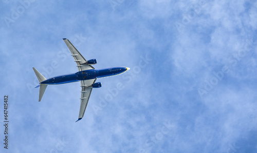 Blue and white airplane shot from the below after takeoff