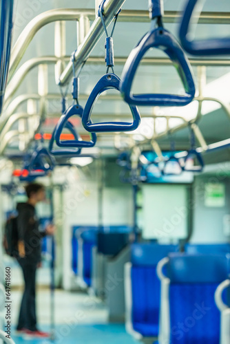 Blurred train interior background, city public transport, passenger handles, lonely passenger