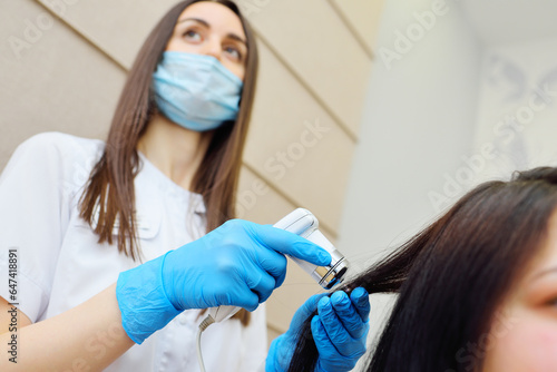 doctor cosmetologist dermatologist diagnoses the condition of the patient's hair using a special device - a trichoscope.