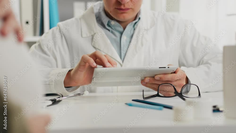 Consultation. A young European man in doctor's clothing reading data on an electronic tablet in a doctor's waiting room. General view of hospital workers, ultrasound data on a tablet, specialist Consultation. A young European man in doctor's clothing reading data on an electronic tablet in a doctor's waiting room. General view of hospital workers, ultrasound data on a tablet, specialist