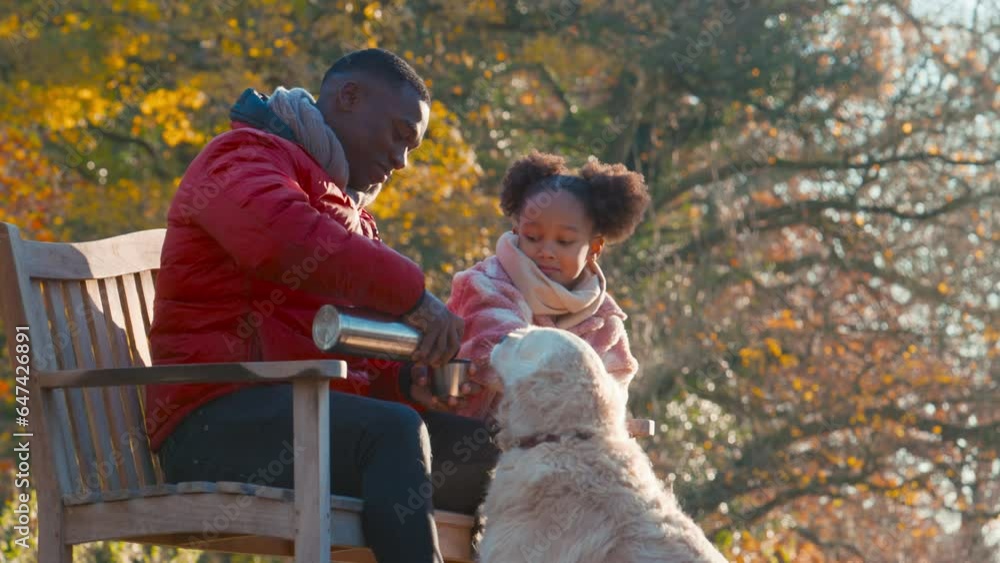 Father pouring hot drink from flask for daughter on walk with dog in autumn countryside - shot in slow motion Father pouring hot drink from flask for daughter on walk with dog in autumn countryside - shot in slow motion