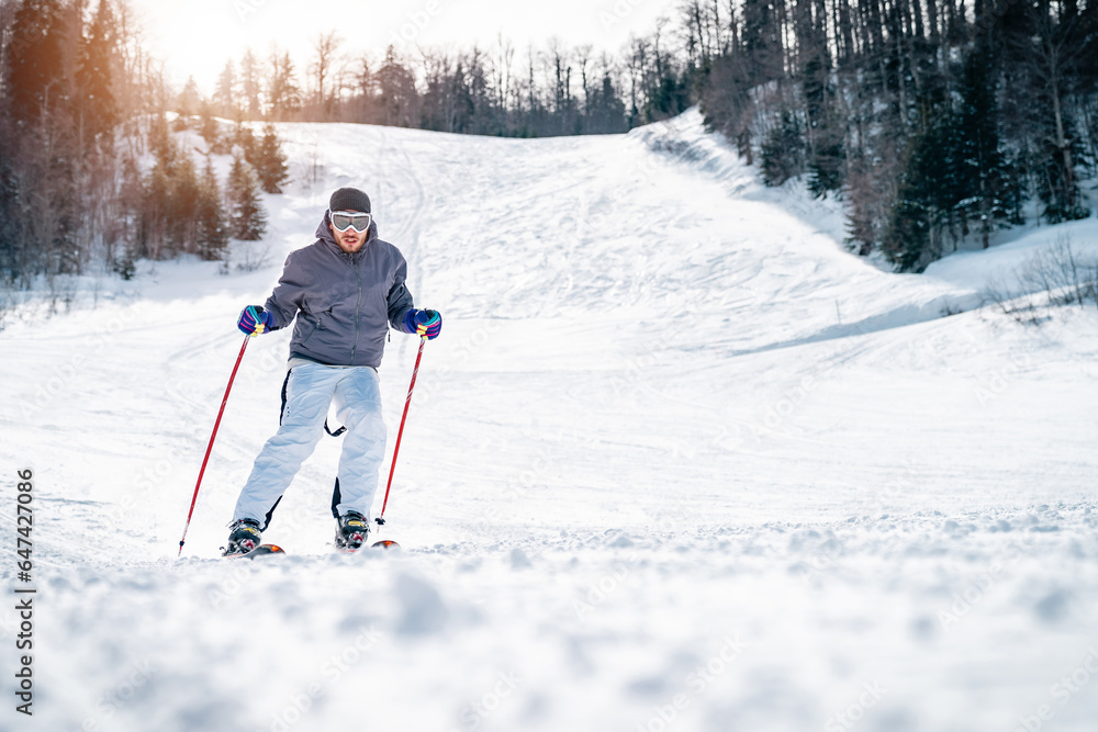 Confident experienced male skier skiing downhill in the mountains. Male skier in movement. Young man enjoying winter sports during the cold sunny day. Confident experienced male skier skiing downhill in the mountains. Male skier in movement. Young man enjoying winter sports during the cold sunny day.