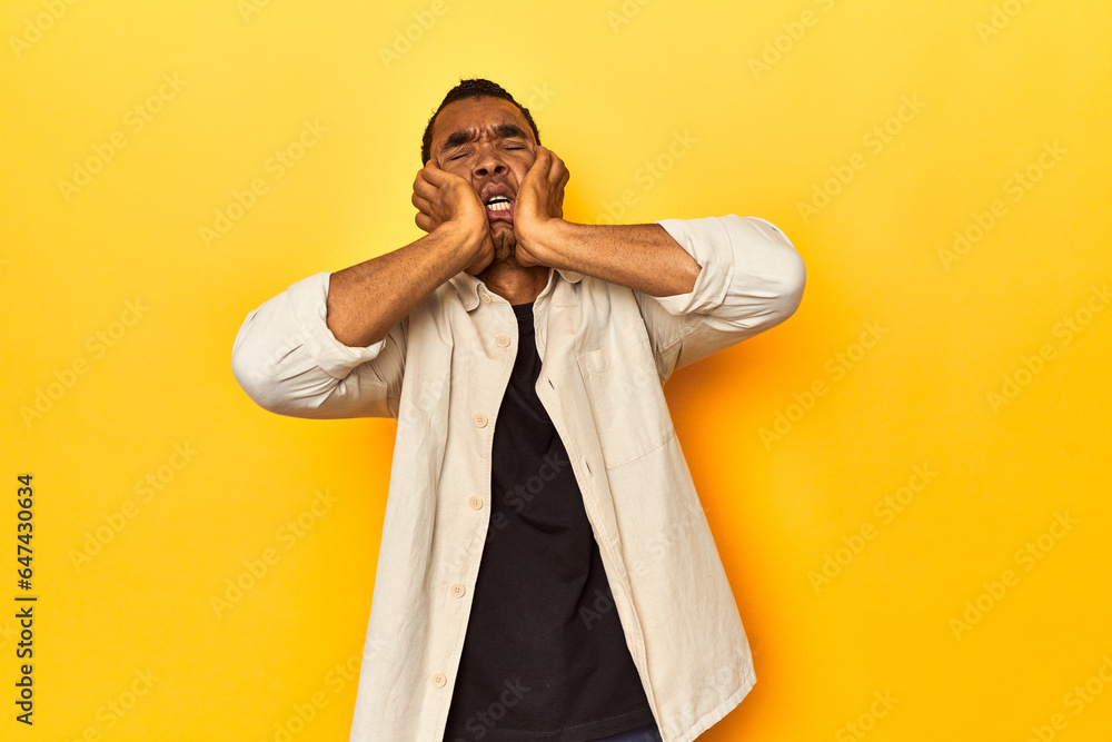 African American man with shirt, yellow studio, crying, unhappy with something, agony and confusion concept. African American man with shirt, yellow studio, crying, unhappy with something, agony and confusion concept.