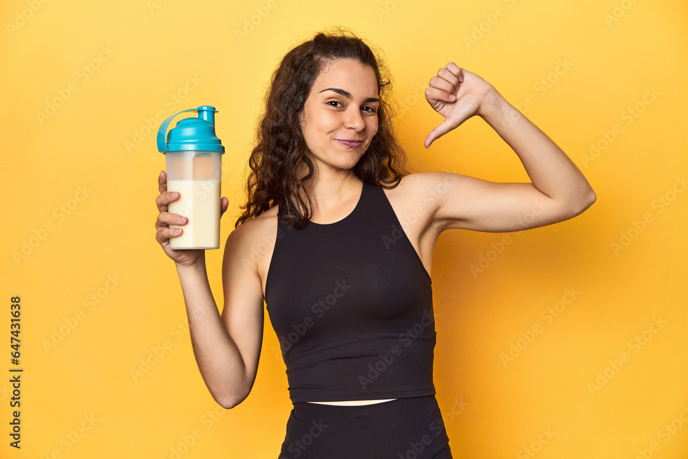Woman holding a protein shake, in sportswear, feels proud and self confident, example to follow. Woman holding a protein shake, in sportswear, feels proud and self confident, example to follow.