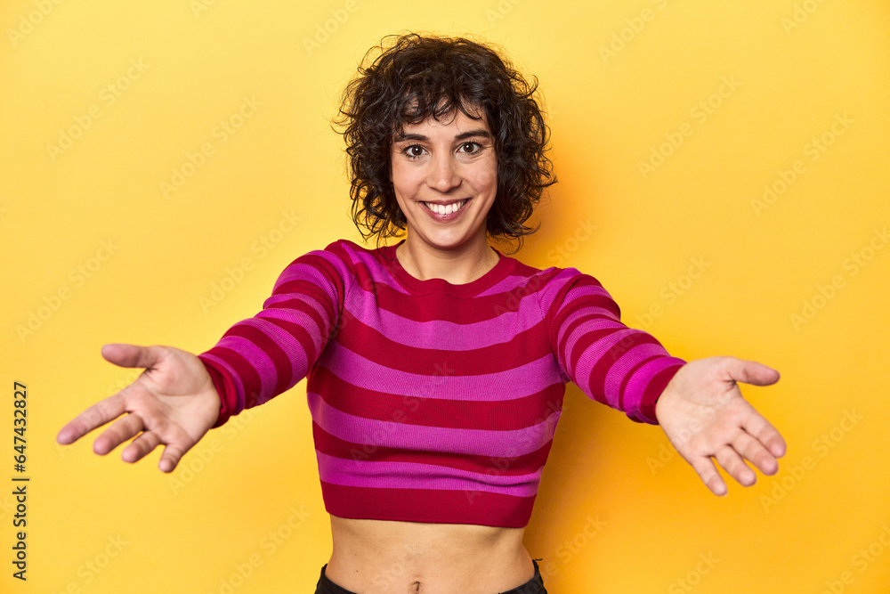 Caucasian curly-haired woman in pink striped-top showing a welcome expression. Caucasian curly-haired woman in pink striped-top showing a welcome expression.