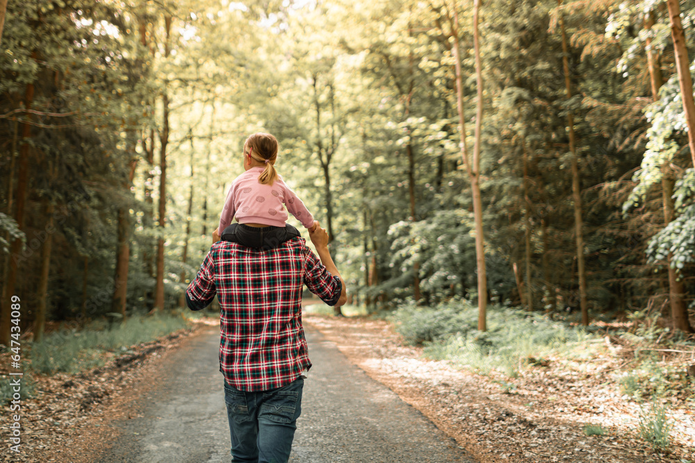 Father giving his child a piggyback walking in the forest enjoying nature Father giving his child a piggyback walking in the forest enjoying nature