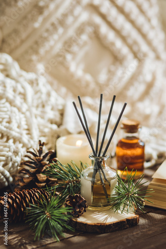 Aroma diffuser, burning candle, pine essential oil and perfume on wooden table. Cozy home decor, hygge and aromatherapy concept. Comfortable atmosphere, fresh smell