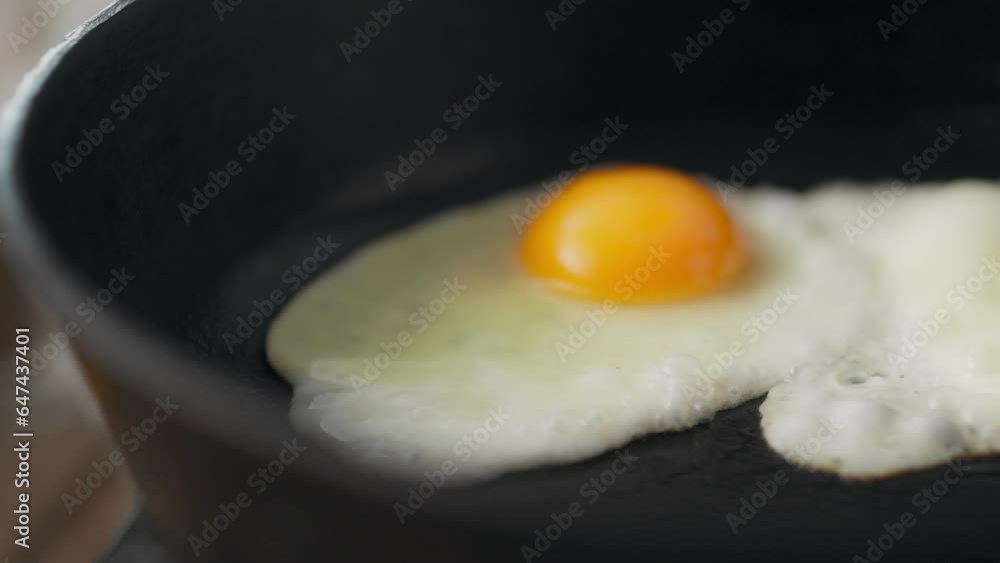 Fry. A happy middle-aged woman in chef's uniform frying eggs in a frying pan in the kitchen at home. Camera in motion, girl following trends, fresh eggs in frying pan, process of preparing an omelette Fry. A happy middle-aged woman in chef's uniform frying eggs in a frying pan in the kitchen at home. Camera in motion, girl following trends, fresh eggs in frying pan, process of preparing an omelette