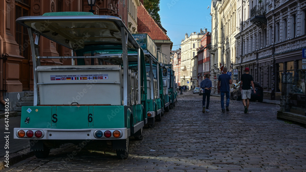 Obraz na płótnie Zielona kolejka turystyczna czeka na przewóz pasażerów po starym mieście miasta Ryga na Łotwie w salonie