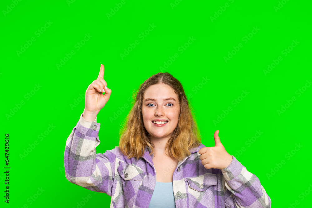 Young woman showing thumbs up and pointing empty place over head, advertising area for commercial text, copy space for goods promotion advertisement. Girl isolated on chroma key background. Lifestyles Young woman showing thumbs up and pointing empty place over head, advertising area for commercial text, copy space for goods promotion advertisement. Girl isolated on chroma key background. Lifestyles