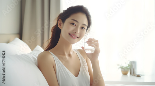 Asian young beautiful woman sitting on bed holding water of glass and drinking in the morning in bedroom at home after wake up in the morning Free Download Asian young beautiful woman sitting on bed holding water of glass and drinking in the morning in bedroom at home after wake up in the morning - GFXLoad