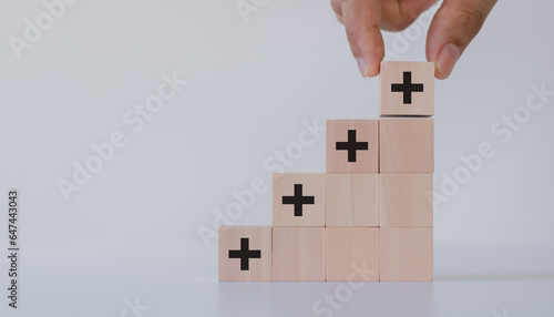Hand putting the wooden cubes with plus sign to offer positive things. Positive things, added value, benefits, additional, personal development, growth mindset, positive thinking, opportunities.