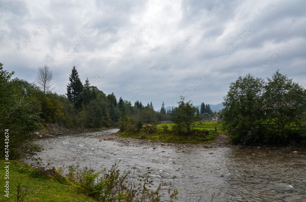 Beautiful landscape of mountain River Prut and trees on shores under sky with rainy clouds in autumn. Vorokhta, Carpathian mountains, Ukraine Beautiful landscape of mountain River Prut and trees on shores under sky with rainy clouds in autumn. Vorokhta, Carpathian mountains, Ukraine