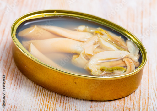 Seafood appetizer. Open can of preserved natural molluscs razorshell (ensis) on wooden table photo