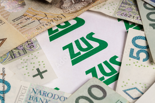 the inscription "ZUS" surrounded by Polish PLN banknotes and zlotys (selective focus)