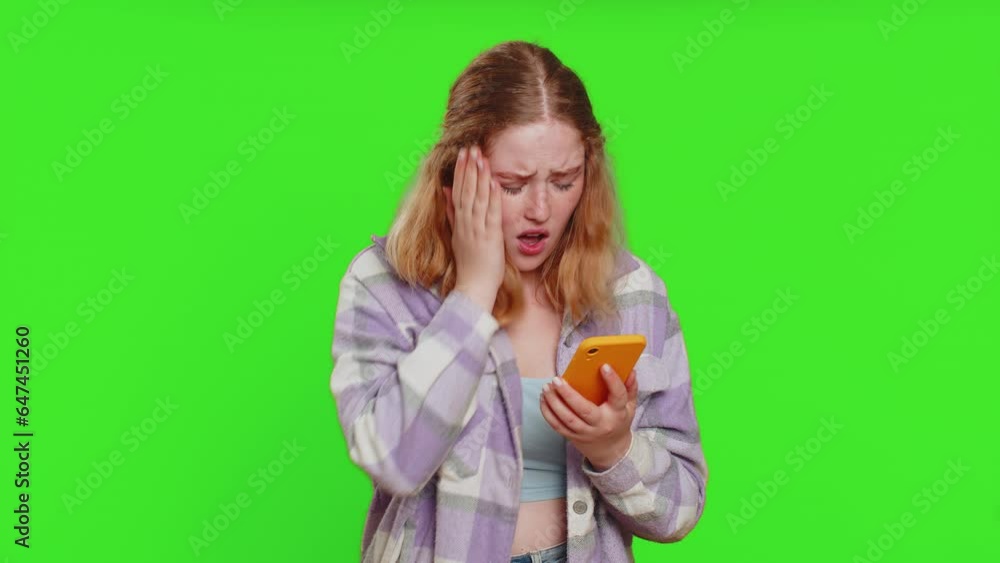Upset sad woman use smartphone typing browsing, play game, loses, surprised by sudden lottery results bad fortune loss fail unlucky news. Sad redhead girl isolated on chroma key background, indoors Upset sad woman use smartphone typing browsing, play game, loses, surprised by sudden lottery results bad fortune loss fail unlucky news. Sad redhead girl isolated on chroma key background, indoors