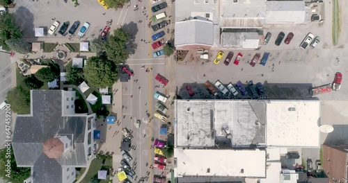 Birds eye drone shot of hotrod cars in the streets of a small town during a car show