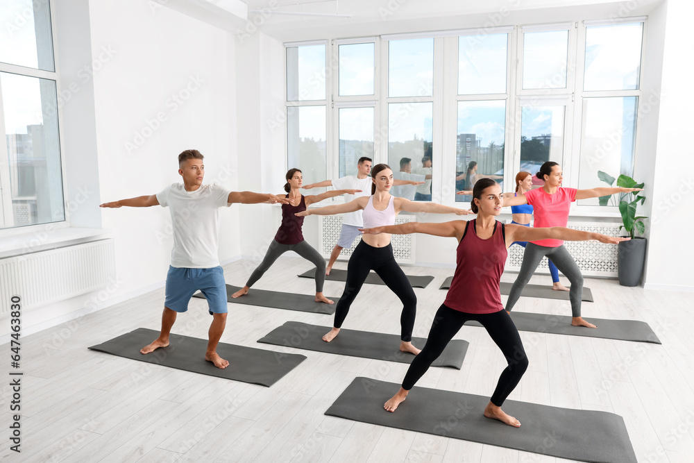 Group of people practicing yoga on mats indoors Group of people practicing yoga on mats indoors